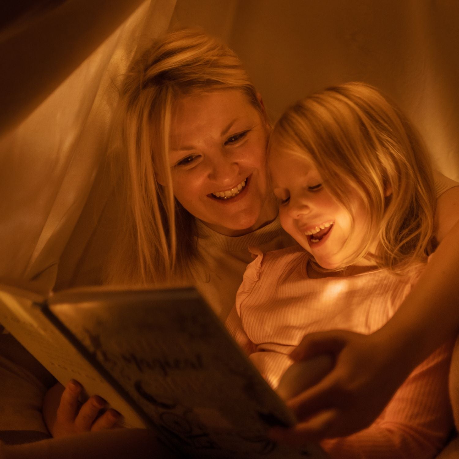 Eine Mutter liest ihrer kleinen Tochter aus einem Buch vor, und verwendet dazu das HerzLicht.